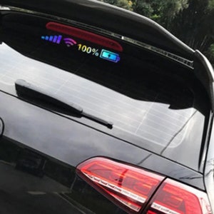 May include: A black car with a rear window sticker that reads "100%" and has a battery icon. The sticker also has a signal strength icon and a wifi icon.