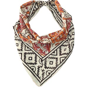 May include: A triangular bandana featuring a cream-coloured base with a black geometric border pattern and a central section decorated with orange and red floral motifs. The fabric is folded into a loop shape, displaying a repeating block-print style design.