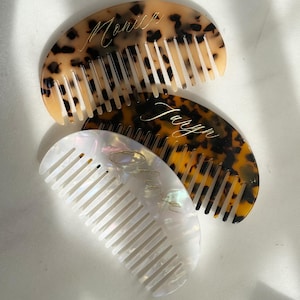 Könnte beinhalten: Drei personalisierte Haarkämme. Einer hat ein Schildpattmuster mit dem Namen "Monica" in goldener Schrift. Ein weiterer hat ein ähnliches Muster mit dem Namen "Taryn". Der dritte Kamm ist weiß mit dem Namen "Olivia".