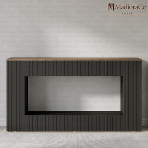 May include: A modern, dark gray table with a rectangular cutout in the center. The table has a ribbed texture on the sides and a light brown wooden top. The table is a contemporary furniture piece.