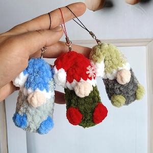 May include: Three crocheted gnome ornaments with different coloured hats and bodies. The gnomes are blue, red, and green. They are attached to keychains.