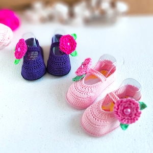 Pu&ograve; includere: Due paia di scarpine per neonati all'uncinetto con fiori rosa e viola. Le scarpine sono realizzate con un filato morbido e hanno un delicato motivo floreale.