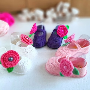 Pu&ograve; includere: Quattro paia di scarpine per neonati all'uncinetto con decorazioni floreali. Due paia sono bianche con fiori rosa, un paio &egrave; viola con un fiore rosa e un paio &egrave; rosa con un fiore rosa.