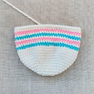 May include: A white crocheted bowl with pink and blue stripes. The bowl is made of a soft, fuzzy yarn.