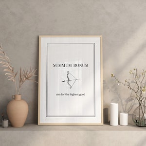 May include: A framed print with a white background and black text that reads "Summum Bonum" and "aim for the highest good". A black and white illustration of an arrow and bow is centered on the print.