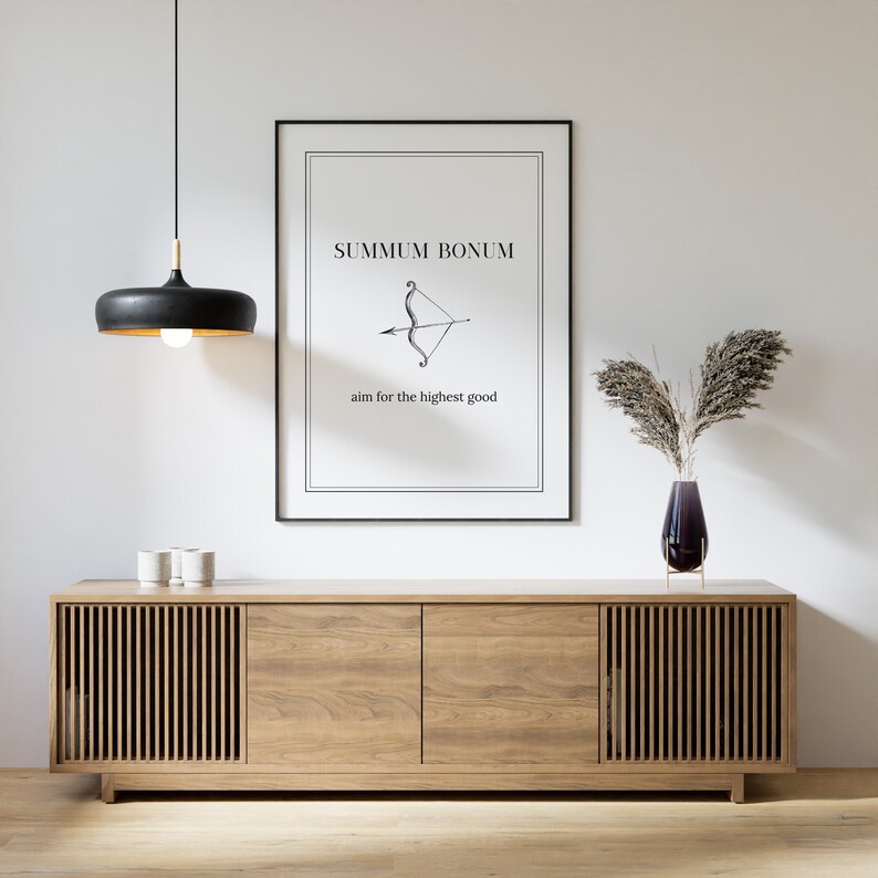 May include: A black and white print with the text "Summum Bonum" and an arrow pointing to the right. The text below the arrow reads "aim for the highest good". The print is hanging on a white wall above a wooden cabinet with two doors.