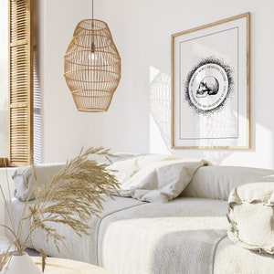 May include: A black and white framed print with a skull and the text "Memento Mori, Memento Vivere, Remember You Are Mortal, Remember To Live". The print is hanging on a white wall above a white sofa with a woven lampshade hanging from the ceiling.