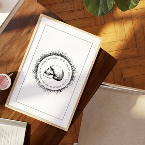 May include: Black and white print of a skull with the text "Memento Mori | Memento Vivere - Remember You Die | Remember To Live" in a circle around it.