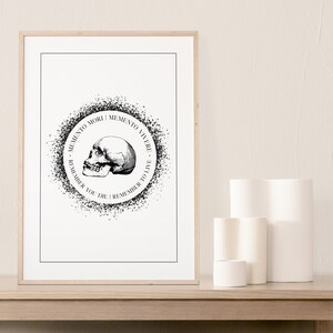 May include: A framed print featuring a black and white illustration of a skull within a circle, inscribed with the text "Memento Mori | Memento Vivere - Remember You Die | Remember To Live".