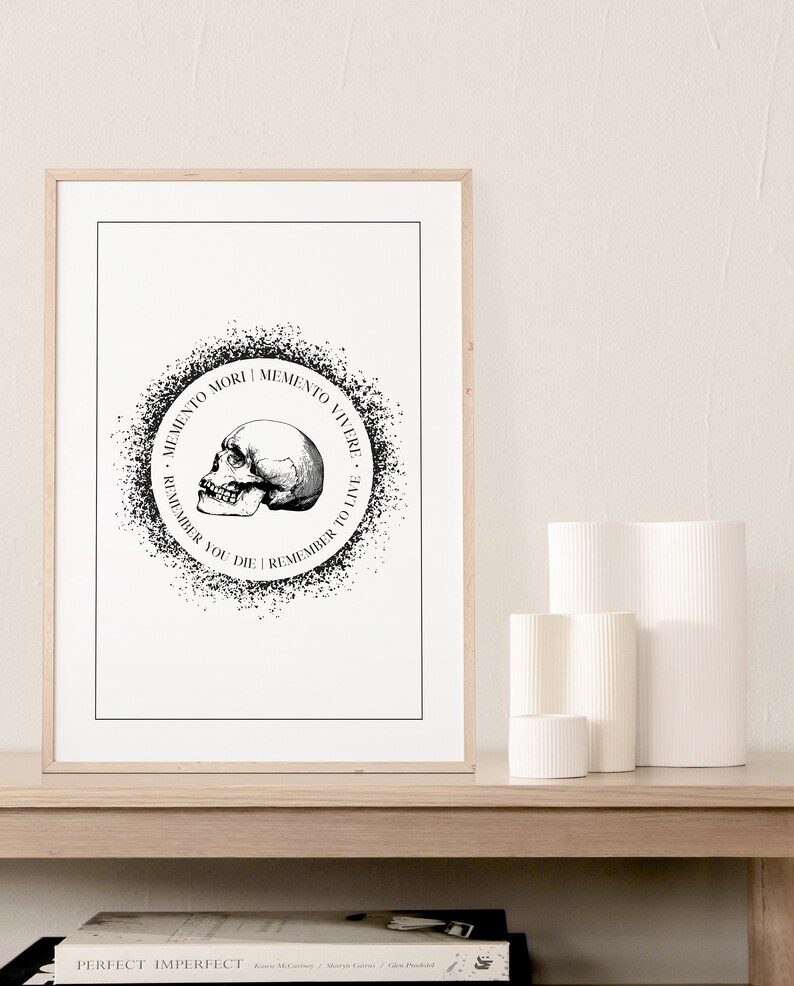 May include: A framed print featuring a black and white illustration of a skull within a circle, inscribed with the text "Memento Mori | Memento Vivere - Remember You Die | Remember To Live".