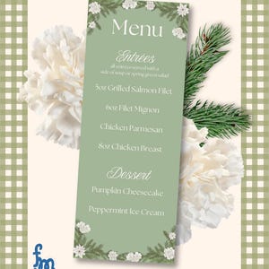 May include: A menu card with a green background, displaying the word "Menu" and a list of dishes. Entrées include Grilled Salmon Filet, Filet Mignon, Chicken Parmesan, and Chicken Breast. Desserts are Pumpkin Cheesecake and Peppermint Ice Cream. The card is decorated with floral and evergreen accents.