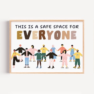 Op de afbeelding: Een ingelijste print met de tekst "THIS IS A SAFE SPACE FOR EVERYONE" in blauw, bruin en beige. De print toont een diverse groep mensen die elkaars hand vasthouden. Het kunstwerk heeft een licht houten frame.