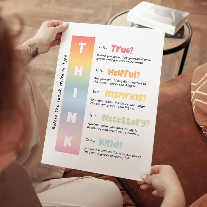 May include: A white poster with the text "THINK" in a vertical gradient of colors. The poster asks questions about truth, helpfulness, inspiration, necessity, and kindness before speaking or writing. The poster is held by a person.