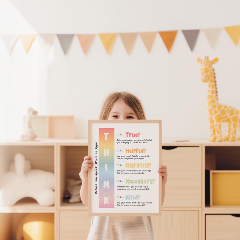May include: A framed poster held by a child, featuring the word "THINK" in a vertical gradient of colors. The poster's text prompts consideration of truth, helpfulness, inspiration, necessity, and kindness before speaking, writing, or typing.