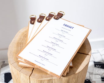May include: A stack of four rectangular wooden menu boards with white paper inserts. Each board features a dark brown leather strap at the top secured with a gold-toned metal rivet and a gold-toned metal ring for hanging. The top menu displays the text FAUGET BREAKFAST MENU followed by a list of breakfast items and prices in blue font.