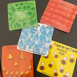 Puede incluir: Una colección de tarjetas cuadradas de colores con varios diseños y texto. Una tarjeta presenta hojas verdes y el texto "A forest full of funds". Otra muestra un patrón de ladrillos con el texto "Build those savings".