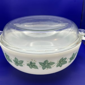 May include: White casserole dish with a glass lid and a green leafy vine design.