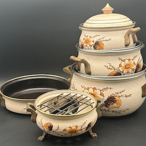 May include: Set of four vintage brown and white ceramic cookware with floral designs. The pots have brass handles and are stacked on top of each other. The top pot has a lid with a brass knob.