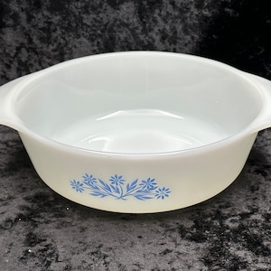 May include: White ceramic baking dish with blue floral design. The dish has two handles on the sides.