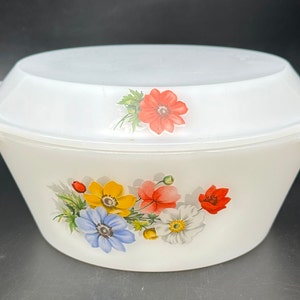 May include: White ceramic casserole dish with a lid. The dish has a floral design with red, yellow, blue, and white flowers.