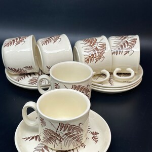 May include: Set of six white ceramic teacups and saucers with a brown fern pattern.