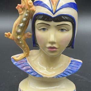 Peut inclure: Buste en céramique d'une femme portant un chapeau bleu et blanc avec un lézard sur l'épaule. La femme a les yeux bleus et les lèvres roses. Le buste est décoré de détails bleus, violets et roses.