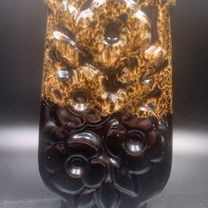 May include: A brown and black ceramic vase with a floral design. The vase is glazed and has a glossy finish.