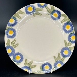 May include: A white ceramic plate with a blue and yellow floral design. The plate has a white centre and a blue and yellow floral border.