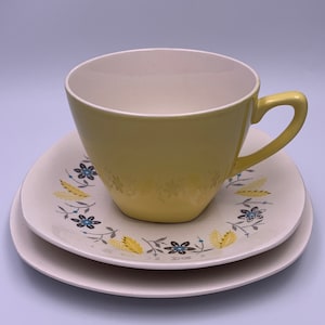 May include: A yellow teacup and saucer set with a floral pattern in shades of yellow, blue and grey.