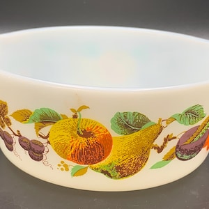 May include: White ceramic baking dish with a fruit design. The design features a pear, apple, plums, and grapes in shades of yellow, orange, red, purple, and green.