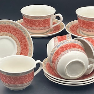 May include: Set of six red and gold teacups and saucers with a floral pattern. The cups and saucers are made of porcelain and have a delicate design.