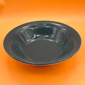 May include: A dark grey ceramic bowl with a white rim. The bowl is round and has a slight lip.