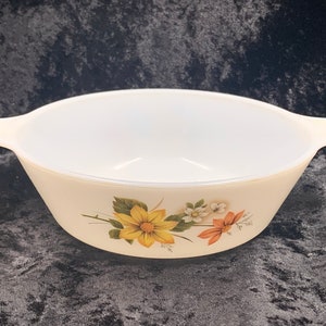 May include: White ceramic baking dish with a floral design featuring yellow, orange, and white flowers. The dish has two handles.
