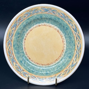 May include: A ceramic plate with a blue and yellow design. The plate has a raised rim with a decorative pattern.