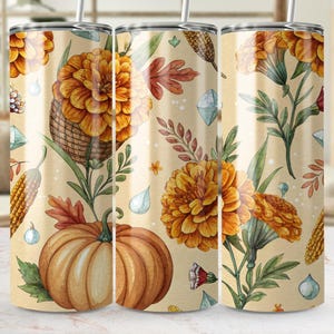 Könnte beinhalten: Ein Edelstahlbecher mit einem herbstlichen Design. Das Design zeigt Aquarellillustrationen von Kürbissen, Ringelblumen, Mais und Herbstlaub. Der Hintergrund ist hellbeige mit einem sich wiederholenden Muster aus kleinen blauen Edelsteinen.
