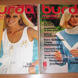Peut inclure: Deux magazines vintage Burda Moden de 1977. Les couvertures présentent des mannequins blonds en vêtements à la mode. L'une a une robe blanche, l'autre un pull bleu. Le texte comprend des conseils de mode et des instructions de couture.
