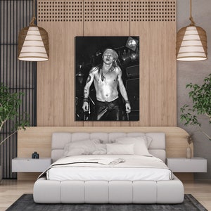 K&ouml;nnte beinhalten: Schwarzwei&szlig;foto eines oben ohne Mannes mit langen Haaren und einem Bandana, der vor einem Mikrofon steht. Das Foto ist gerahmt und h&auml;ngt an einer Wand in einem modernen Schlafzimmer mit einem wei&szlig;en Bett, einem Holz-Kopfteil und zwei H&auml;ngelampen.