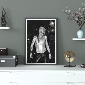 K&ouml;nnte beinhalten: Schwarzwei&szlig;foto eines oben ohne Mannes mit langen Haaren und einem Bandana, der in ein Mikrofon singt. Das Foto ist in einem schwarzen Rahmen gerahmt.