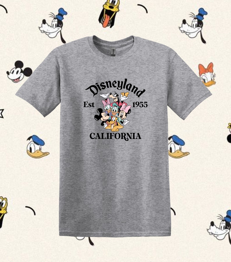 May include: A gray t-shirt with a black graphic of Mickey Mouse, Minnie Mouse, Donald Duck, Goofy, Pluto, and Daisy Duck. The graphic is surrounded by the text "Disneyland Est 1955 CALIFORNIA".