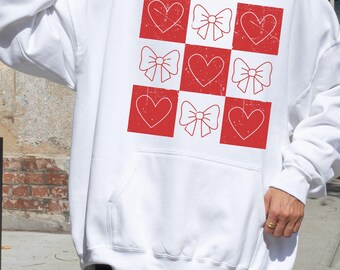 May include: White hoodie with a red and white checkered pattern featuring hearts and bows.