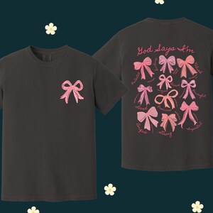 May include: Two black t-shirts with pink bows and the text "God says I'm" with a list of positive words. The words are: "valued, precious, loved, unique, strong, spirited, creative, gifted, beautiful, blessed, worthy".