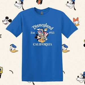 May include: A royal blue t-shirt with a white graphic of Mickey Mouse, Minnie Mouse, Donald Duck, Goofy, and Pluto. The graphic includes the text "Disneyland Est 1955 California".