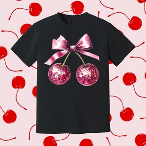 May include: Black t-shirt featuring a pink bow and two cherries with a sparkly pink design.