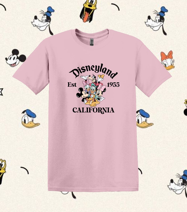 May include: Pink t-shirt with a black graphic of Mickey Mouse, Minnie Mouse, Donald Duck, Goofy, and Pluto. The graphic says "Disneyland Est 1955 California".