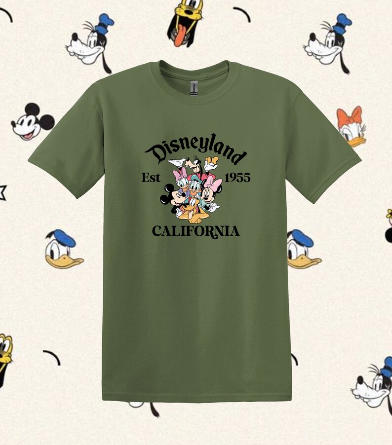 May include: A green t-shirt with a black graphic of Mickey Mouse, Minnie Mouse, Donald Duck, Goofy, Pluto, and a cartoon dog. The graphic includes the text "Disneyland Est 1955 California".