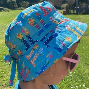 Peut inclure: Un chapeau bob bleu avec un motif coloré de bottes et de fleurs. Le chapeau a une attache à l'arrière et est fait d'un tissu doux en coton.