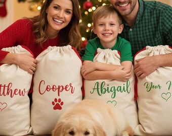 May include: A family poses with personalized Christmas gift bags. The bags are cream-colored with red or green text and accents. The names "Matthew", "Cooper", "Abigail", and "Your Name" are printed on the bags. A golden retriever dog is lying on the floor.