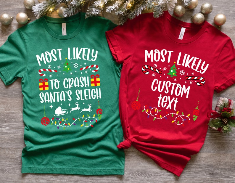 May include: Two Christmas themed t-shirts. The green shirt says "Most Likely to Crash Santa's Sleigh" with a Christmas tree, candy canes, snowflakes, and presents. The red shirt says "Most Likely Custom Text" with a Christmas tree, candy canes, snowflakes, and ornaments.