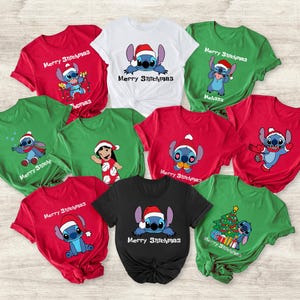 Peut inclure: Plusieurs t-shirts de No&euml;l rouges, verts, blancs et noirs. Chaque t-shirt pr&eacute;sente un personnage de dessin anim&eacute; avec un bonnet de P&egrave;re No&euml;l et le texte "Merry Stitchmas".