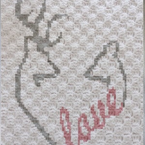 May include: A white crocheted blanket with a gray deer head and the word "love" in pink.